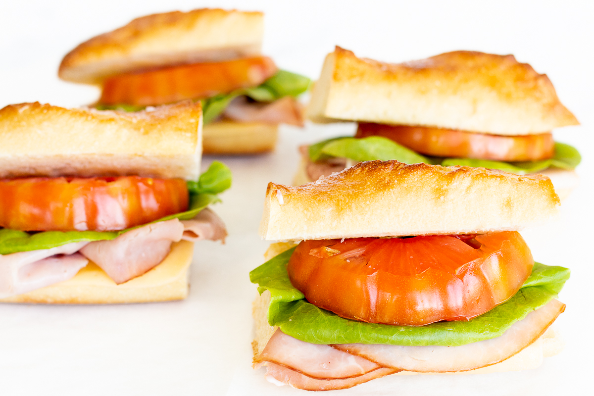 A picnic sandwich with tomatoes, lettuce, and ham.