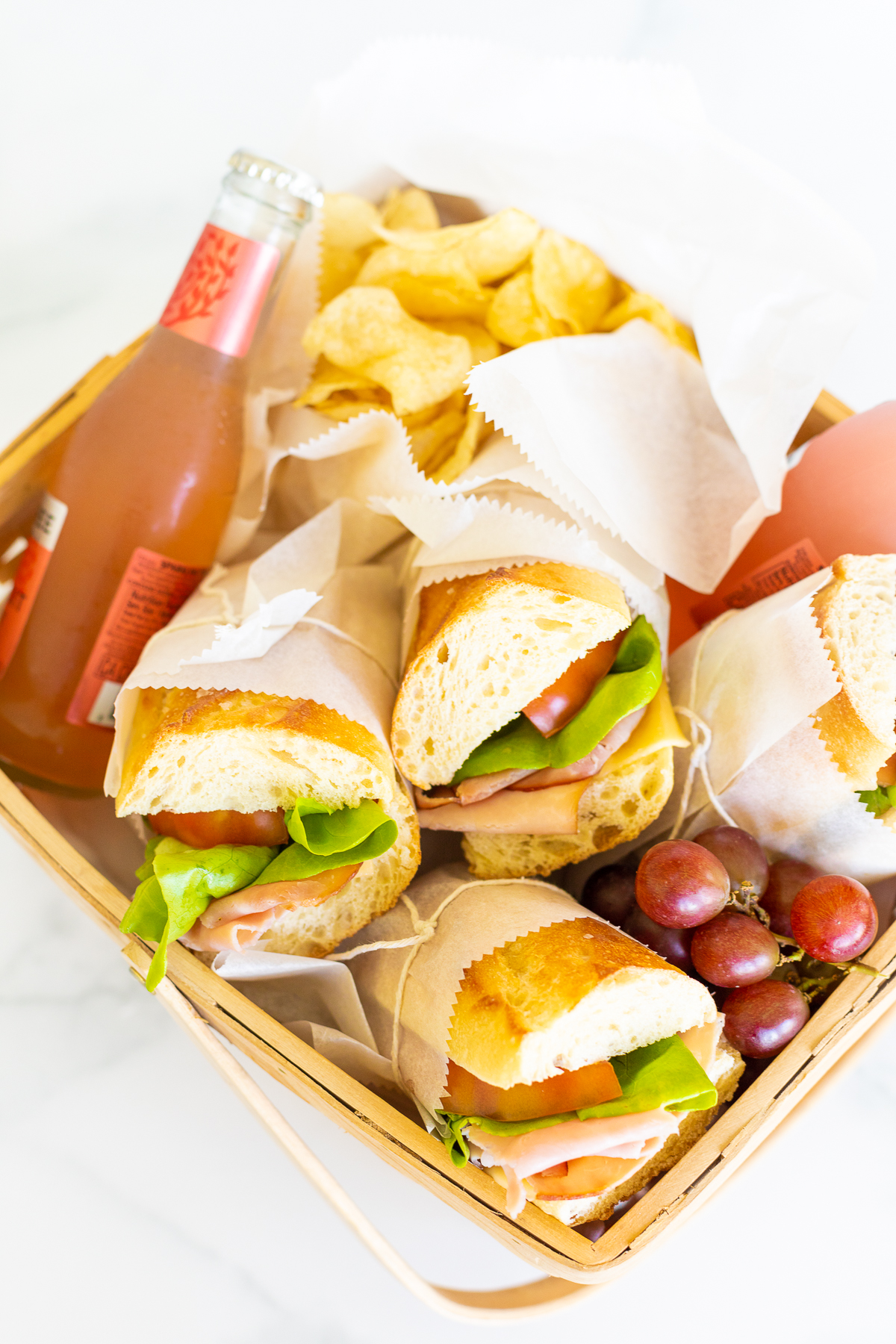 A picnic basket filled with sandwiches and grapes.