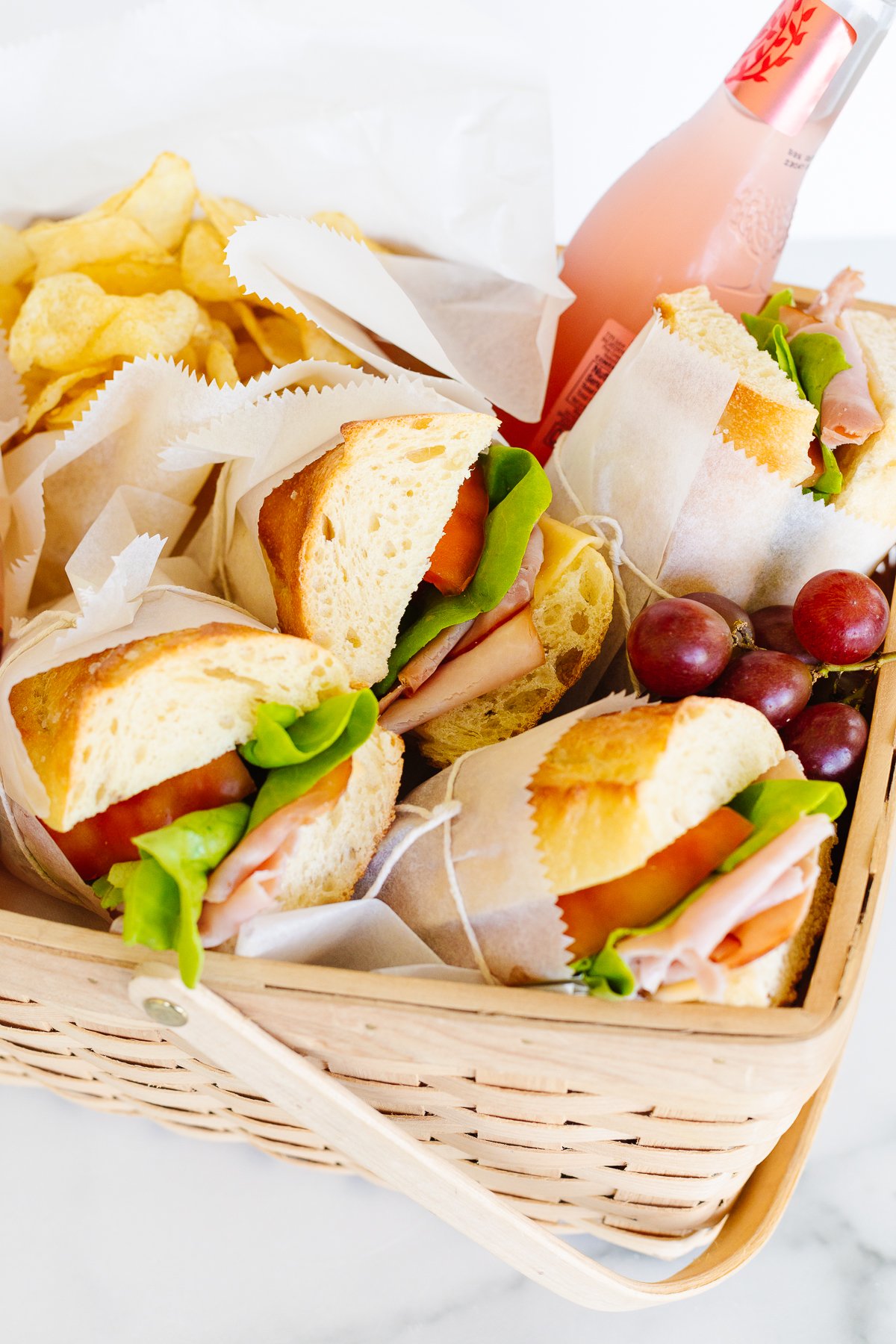 A picnic basket filled with sandwiches and chips.