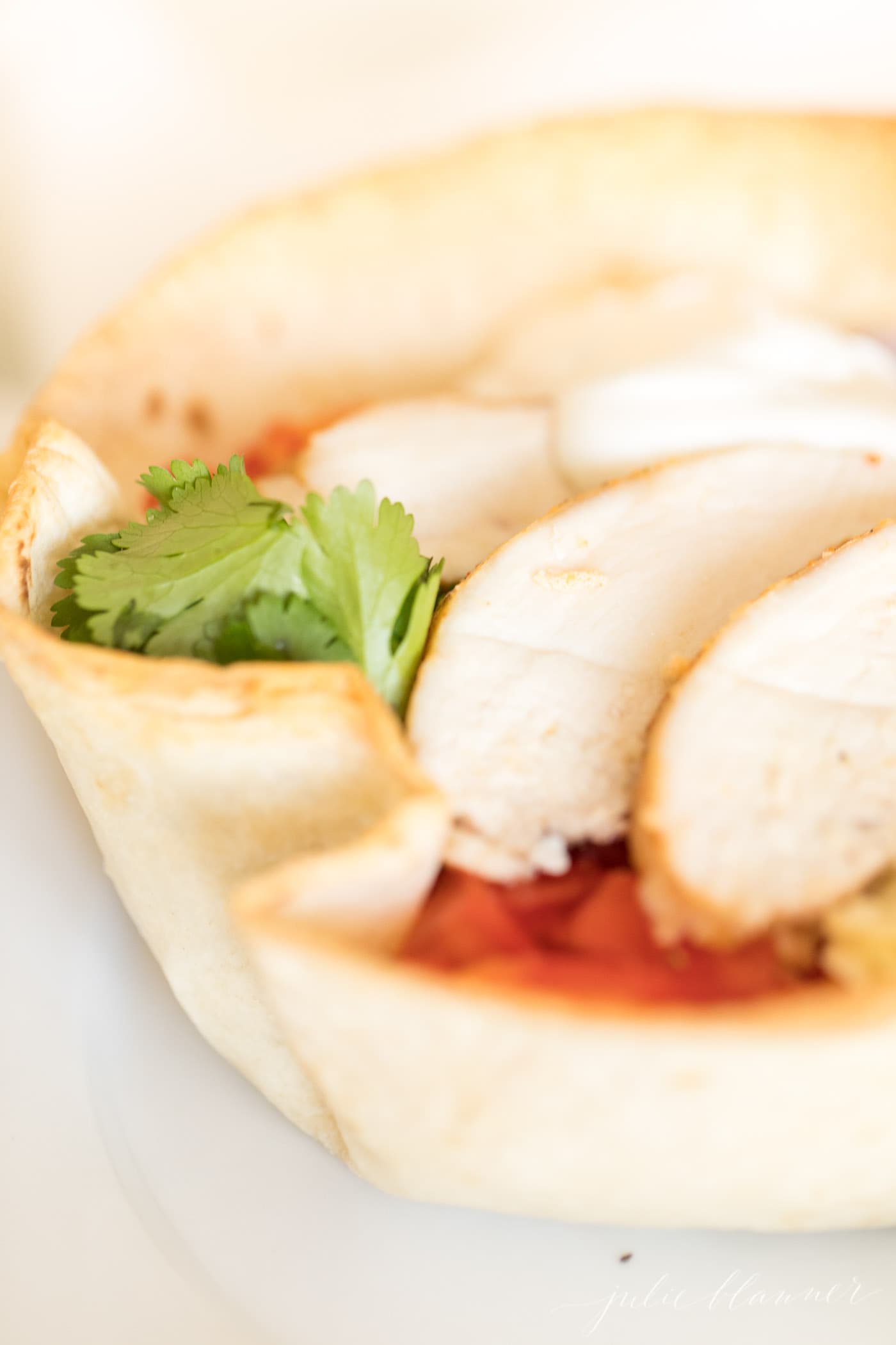 chicken taco salad in a tortilla bowl on a white plate