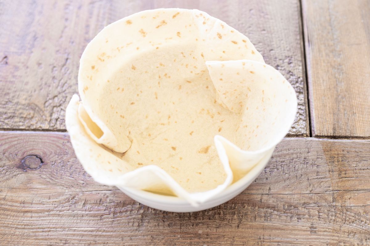 A flour tortilla folded into a bowl for a taco salad bowl recipe.