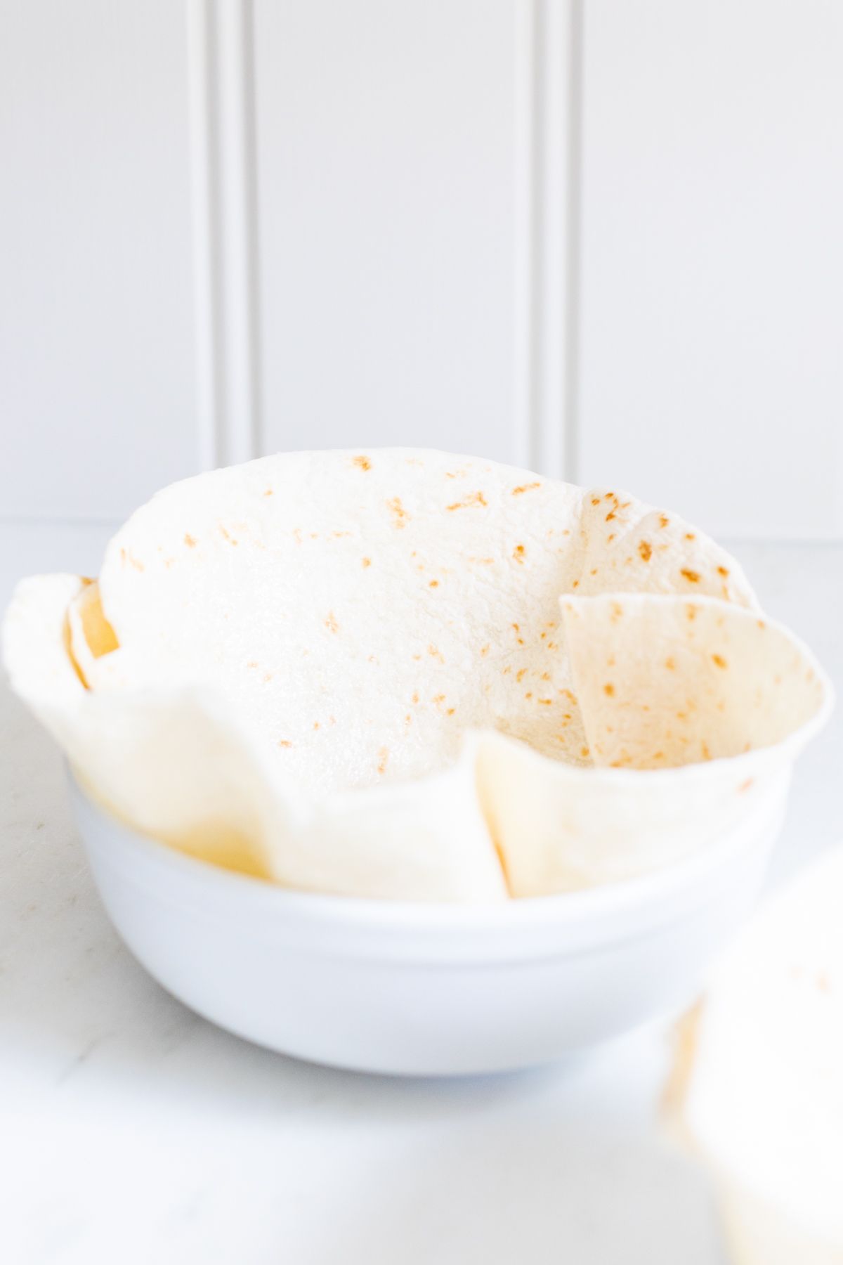 A flour tortilla folded into a bowl for a taco salad bowl recipe.