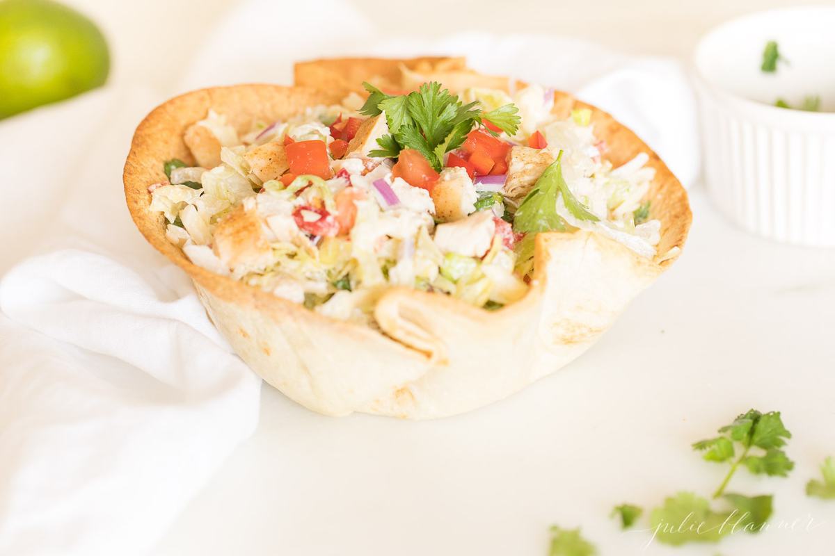 taco salad in a tortilla bowl on a white surface