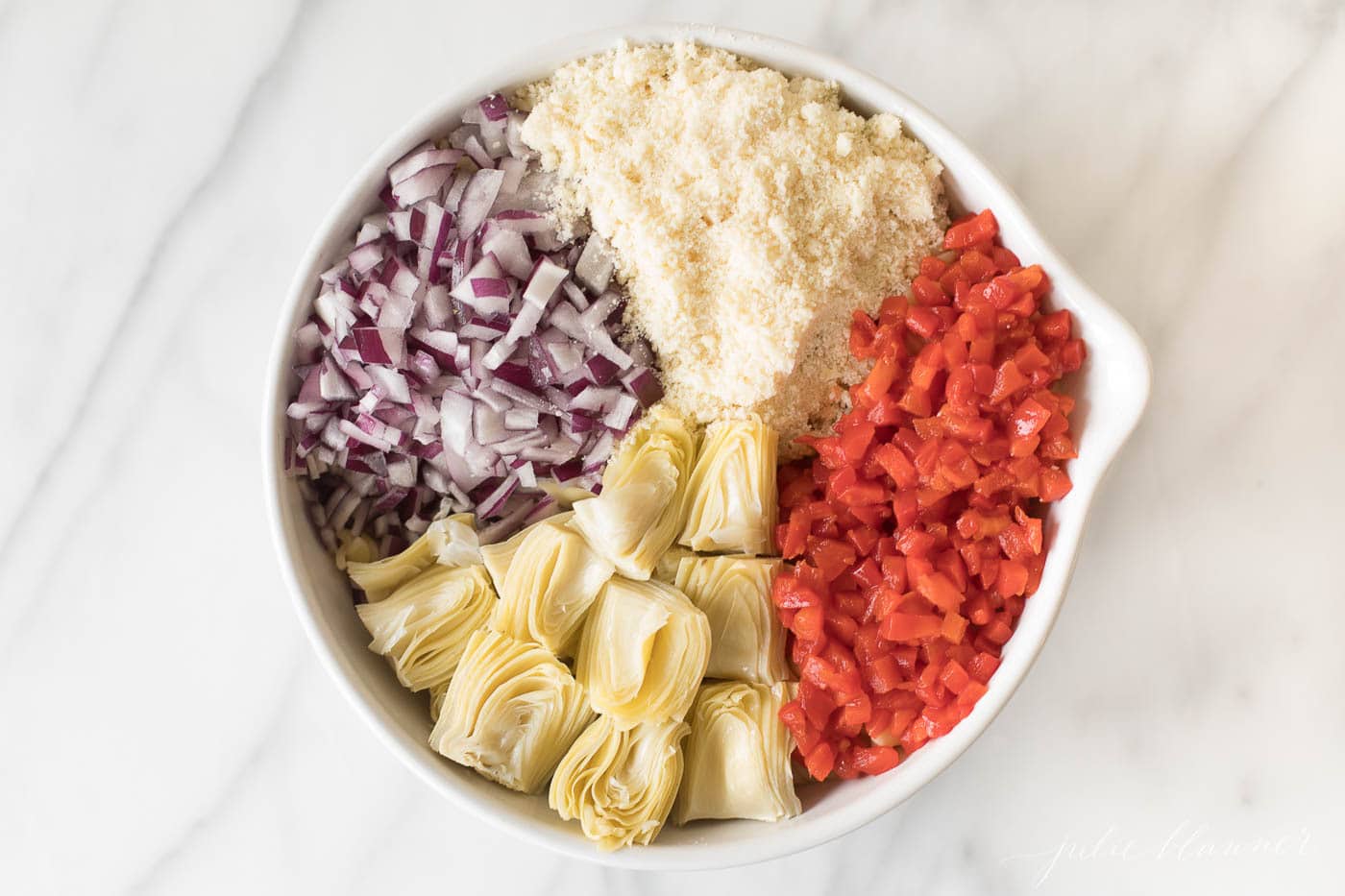 Italian pasta salad ingredients prior to being mixed in a white bowl.