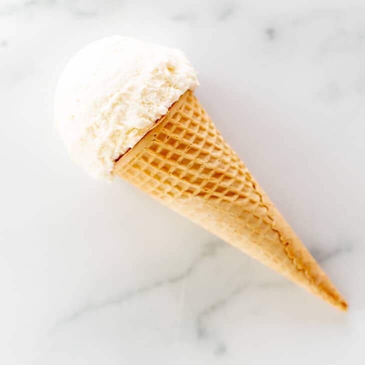 scoop of marshmallow ice cream in sugar cone laying on marble surface