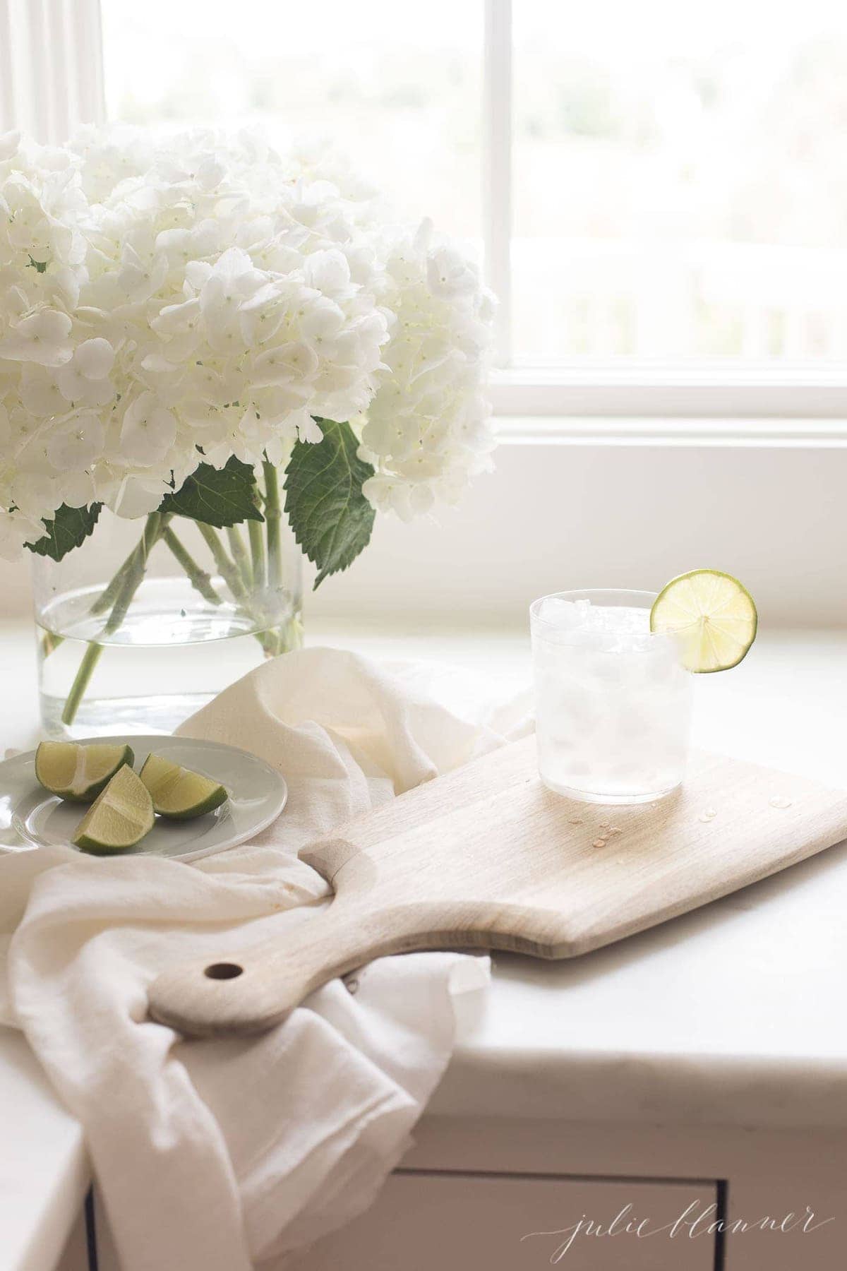 A paloma drink in a kitchen with a white flower arrangement in background.