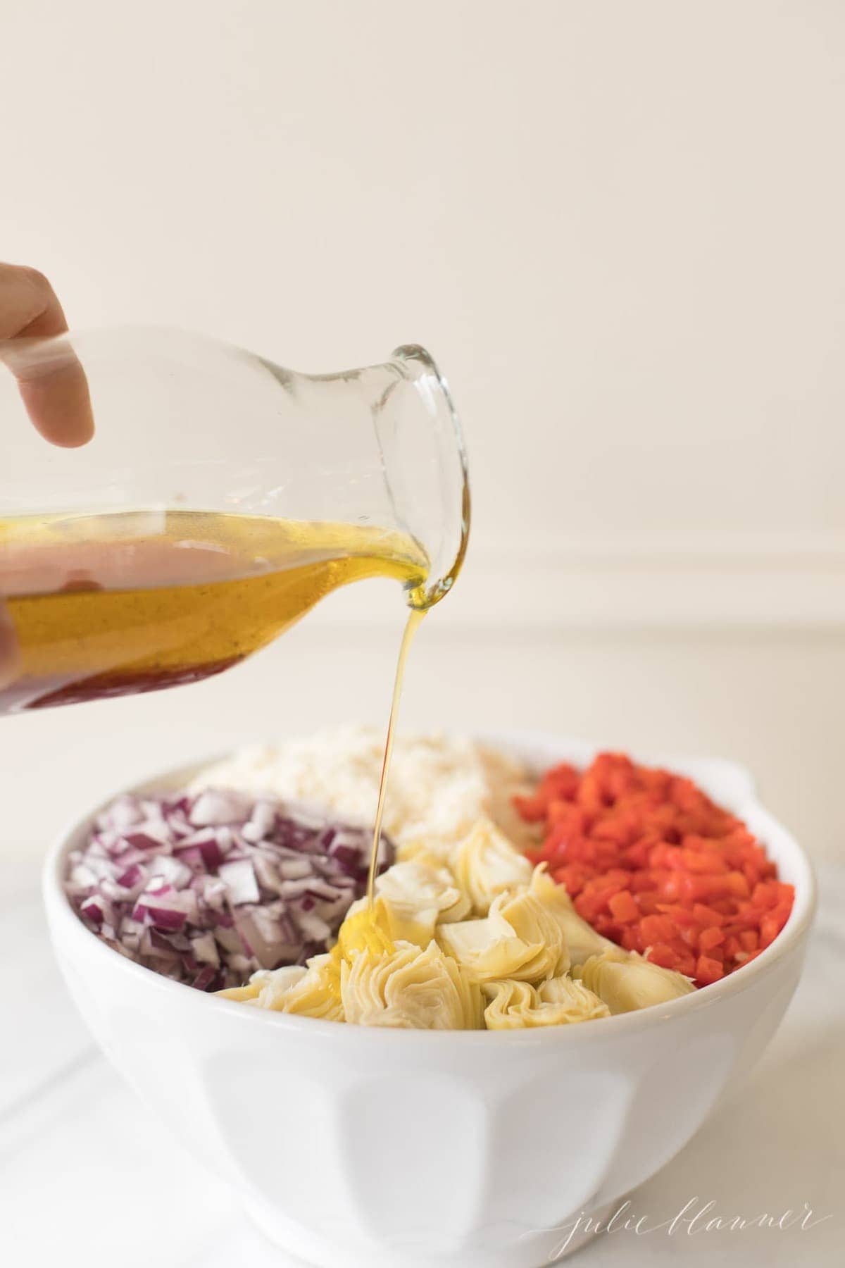 Italian pasta salad dressing being poured over the salad ingredients