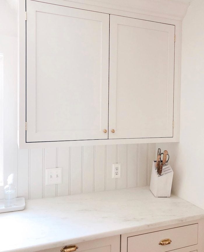 A cream kitchen with organized kitchen counters and a white knife block set