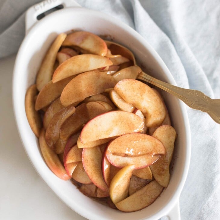 baked apple slices in a white oval baking pan