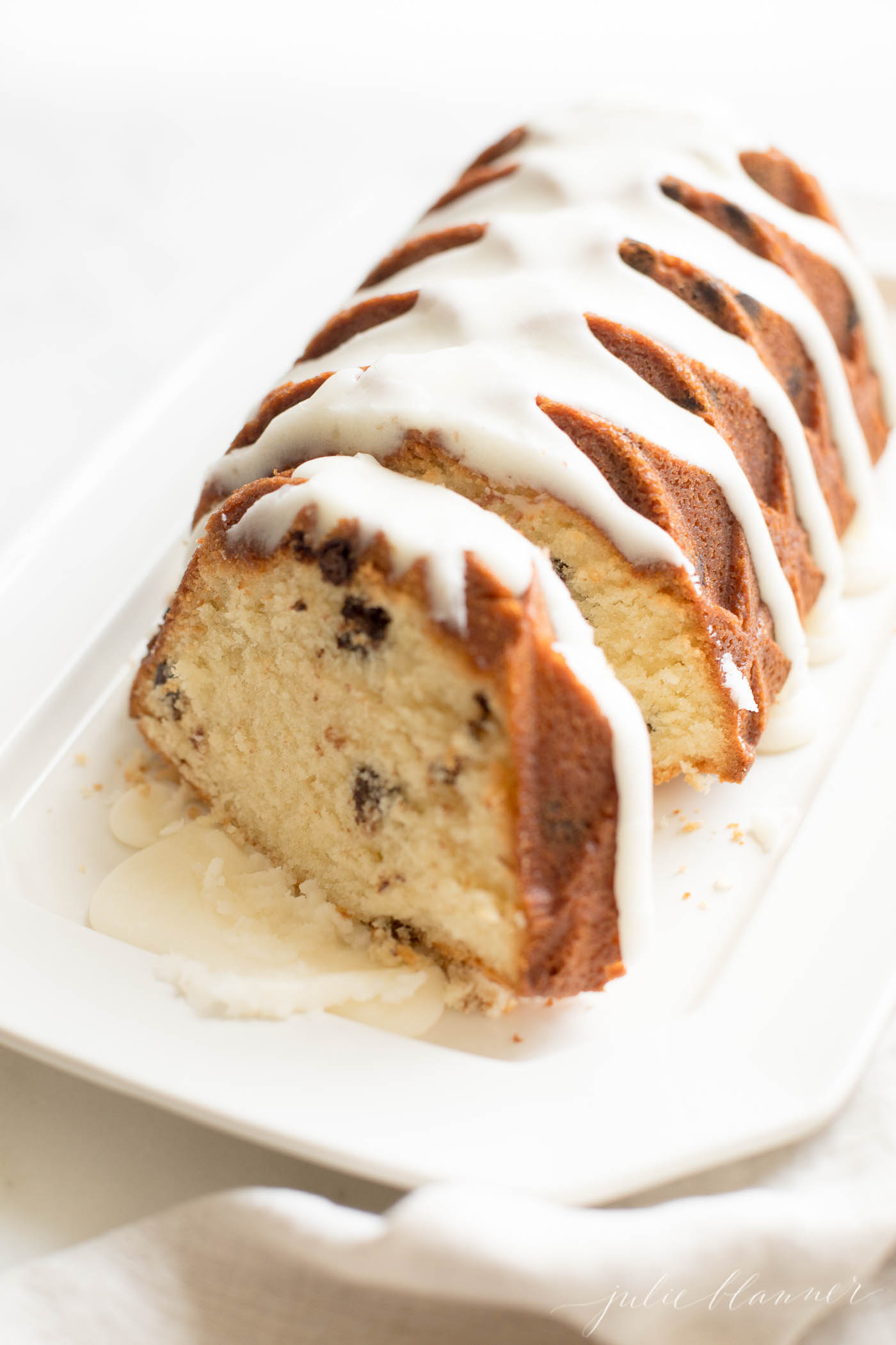 chocolate chip pound cake shaped in a decorative loaf, glazed with icing, resting on a white platter