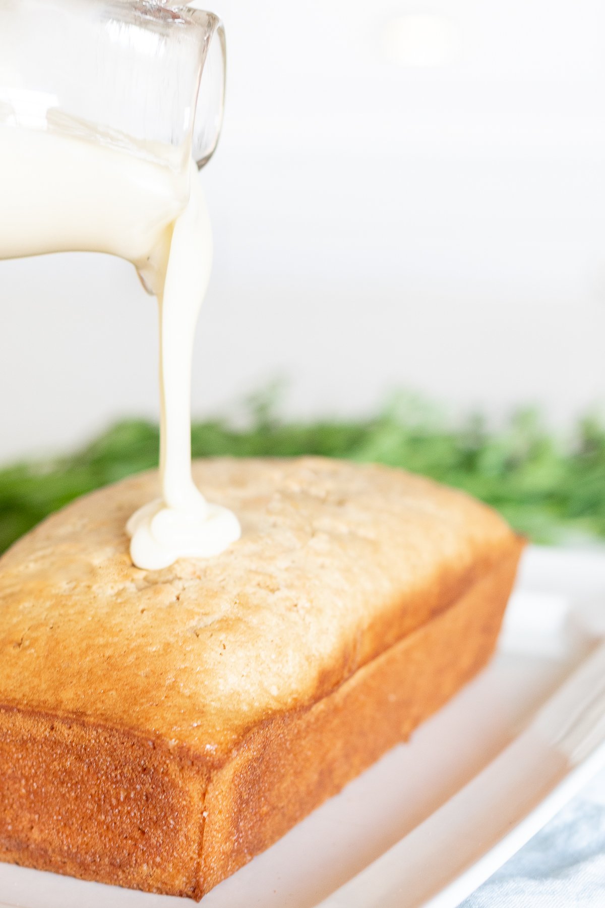 Pouring cream cheese glaze over a freshly baked loaf of bread.