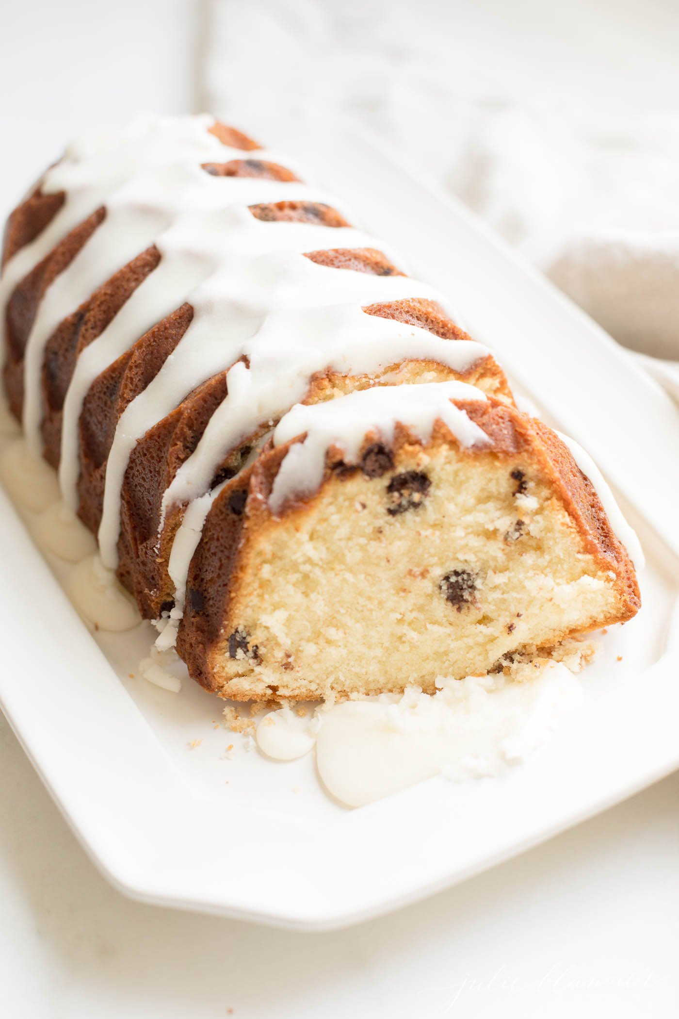 A chocolate chip pound cake on a white serving platter