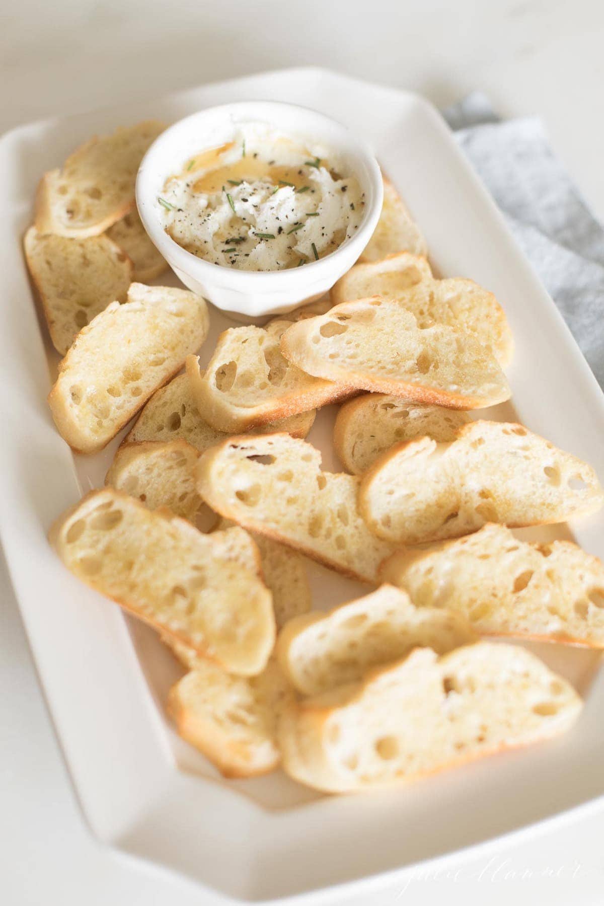 whipped goat cheese on a white platter with crostini