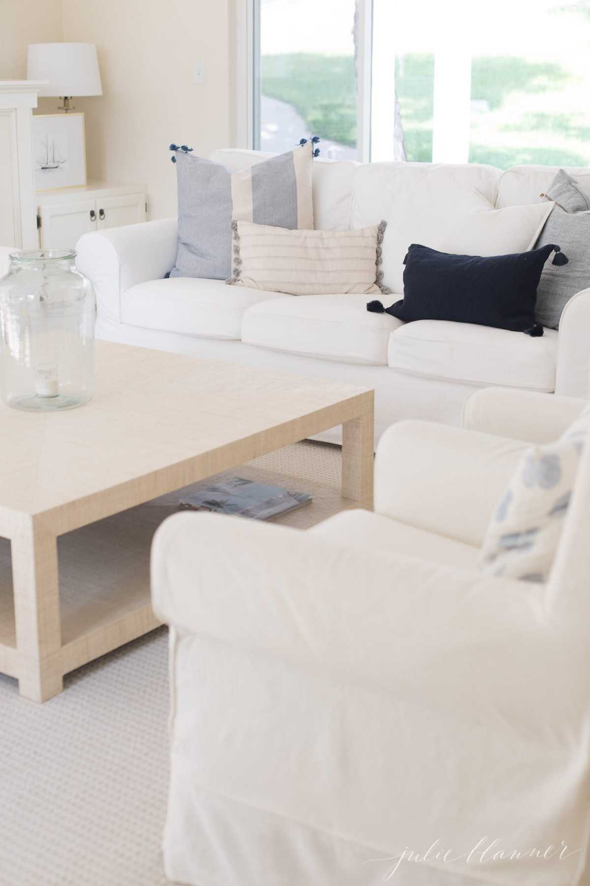 A white living room with a white sofa and blue pillows.