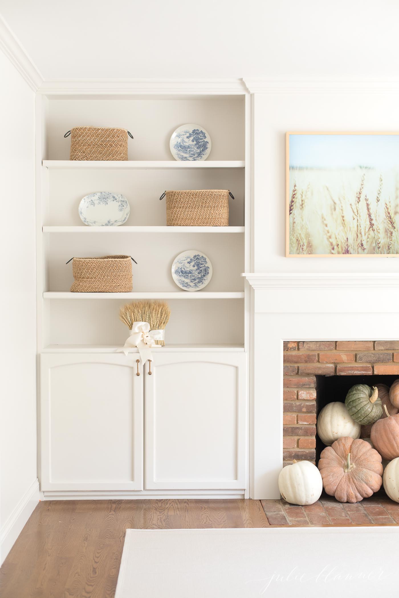 Fall living room decor in a cream living room with a brick fireplace and built in shelves