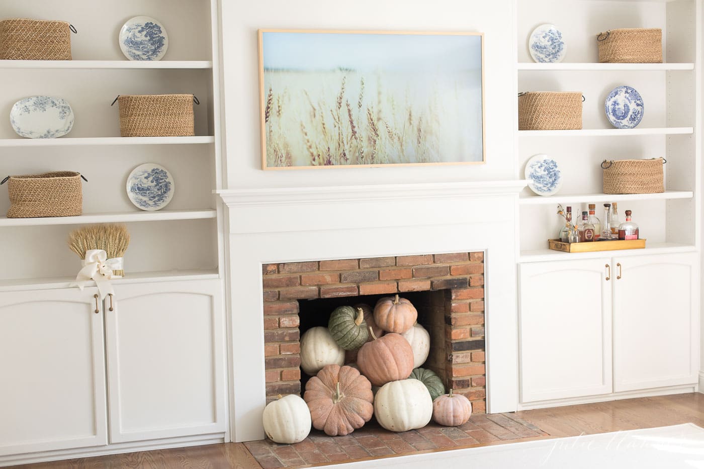 Fall living room decor in a cream living room with a brick fireplace and built in shelves