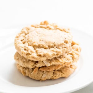 A stack of three delicious oatmeal coconut cookies sits invitingly on a pristine white plate.