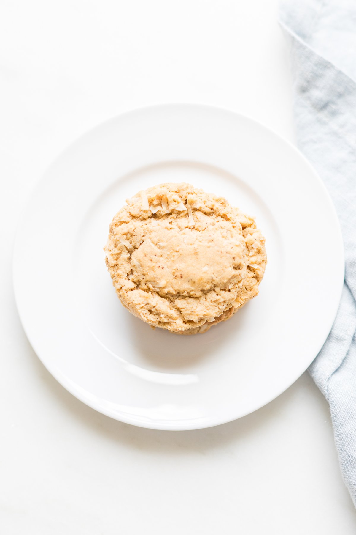 An oatmeal coconut cookie on a white plate.