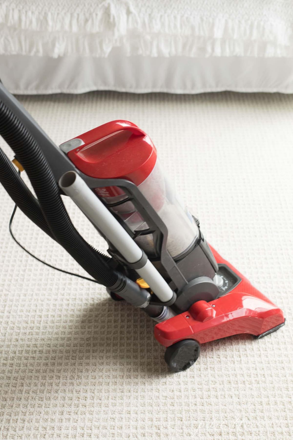 patterned carpet in a bedroom, red vacuum in motion.