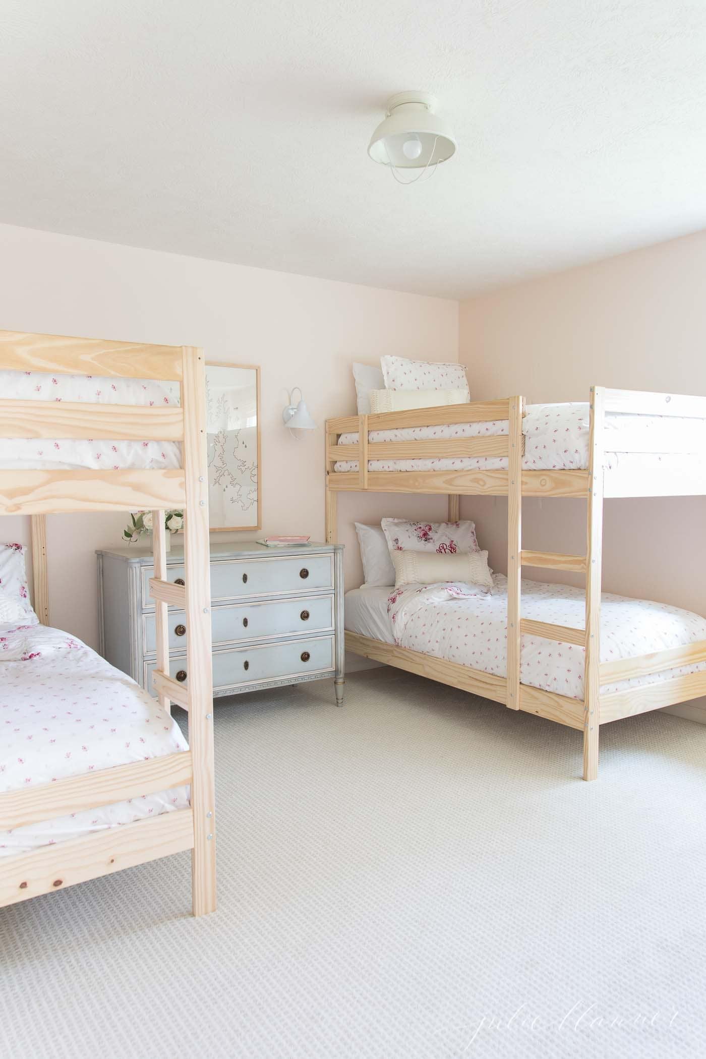 A girls bedroom with wooden bunk beds and floral bedding