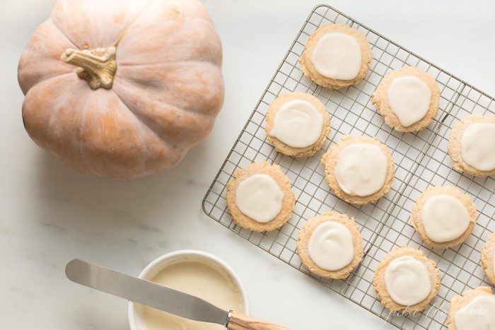 Soft, chewy Pumpkin Sugar Cookies that melt-in-your mouth!. You'll love this Pumpkin Sugar Cookie Recipe with a Cream Cheese Glaze for a little fall flavor! pumpkin sugar cookies with cream cheese glaze on a cooling rack