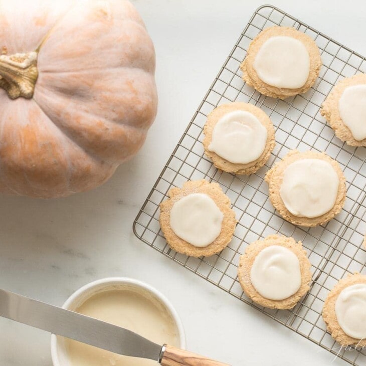 pumpkin sugar cookies with cream cheese glaze on a cooling rack