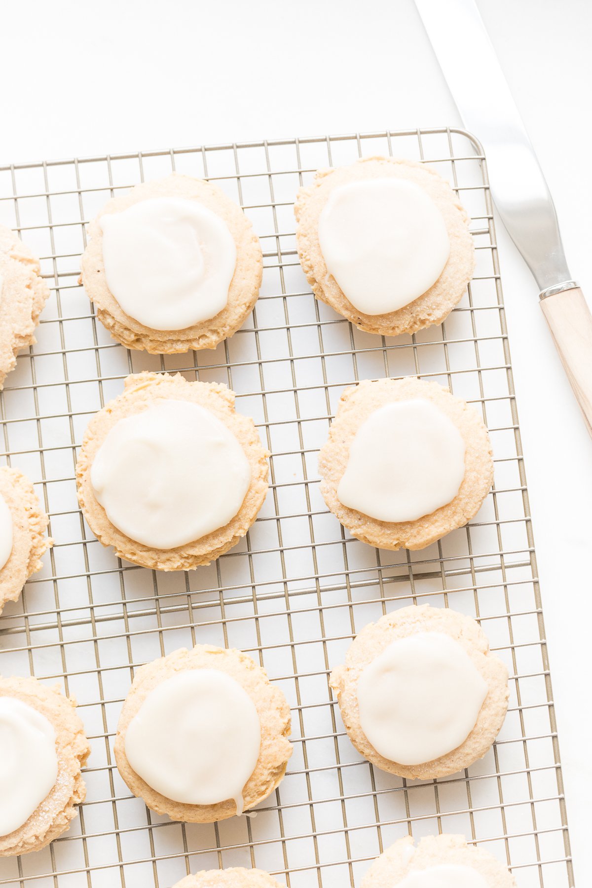 pumpkin sugar cookies with cream cheese glaze on a cooling rack