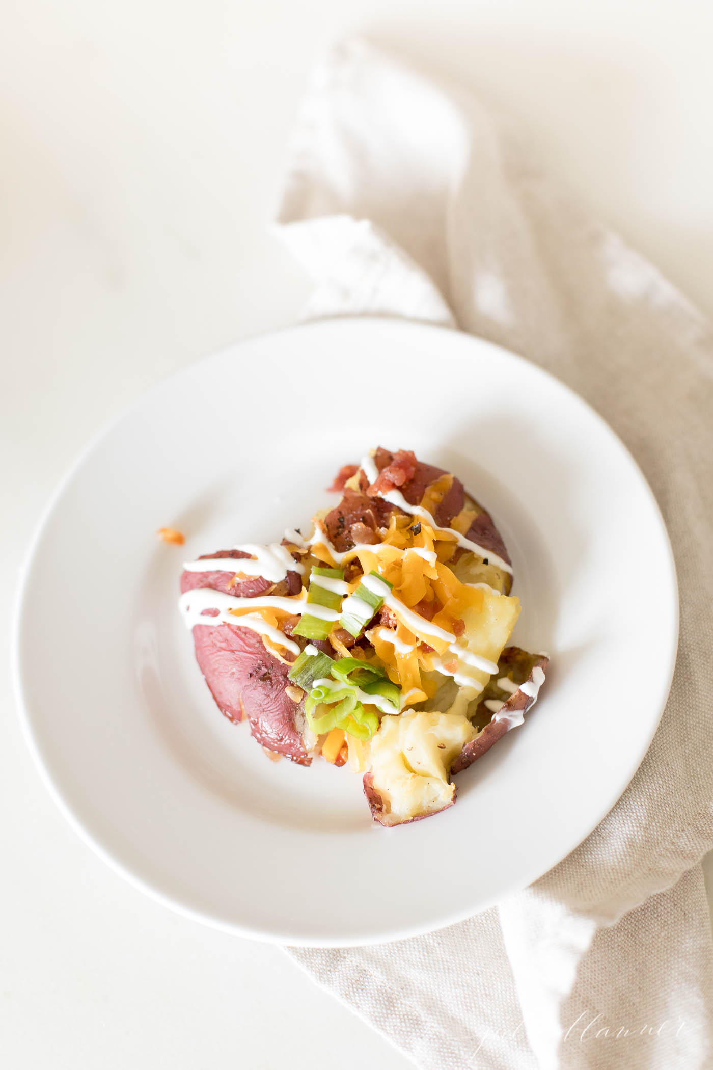 red potato with cheese sour cream and green onion on white plate
