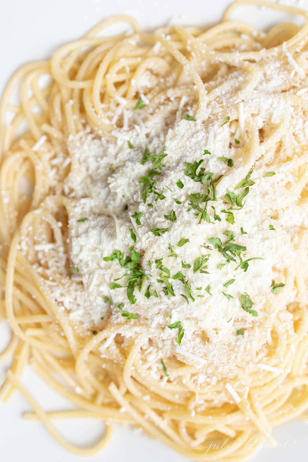 spaghetti with mizithra cheese garnished with parsley