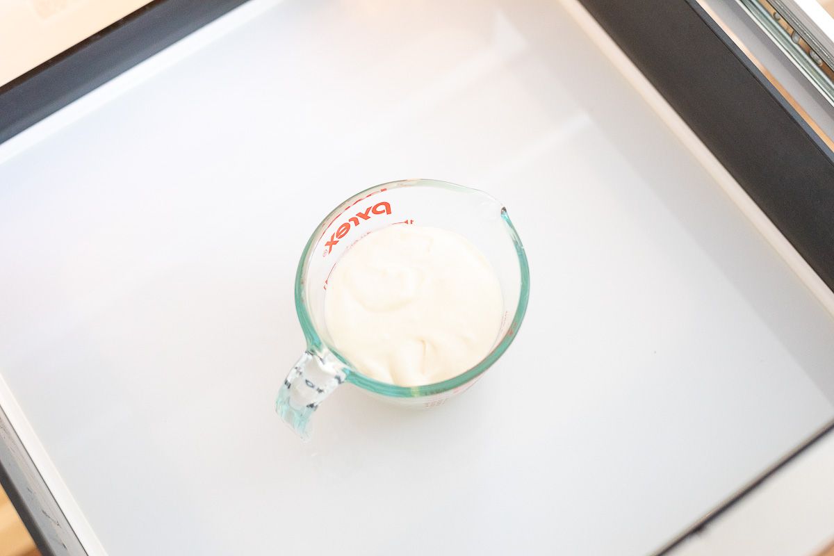 Cinnamon roll icing in a Pyrex measuring bowl, in the drawer of a microwave