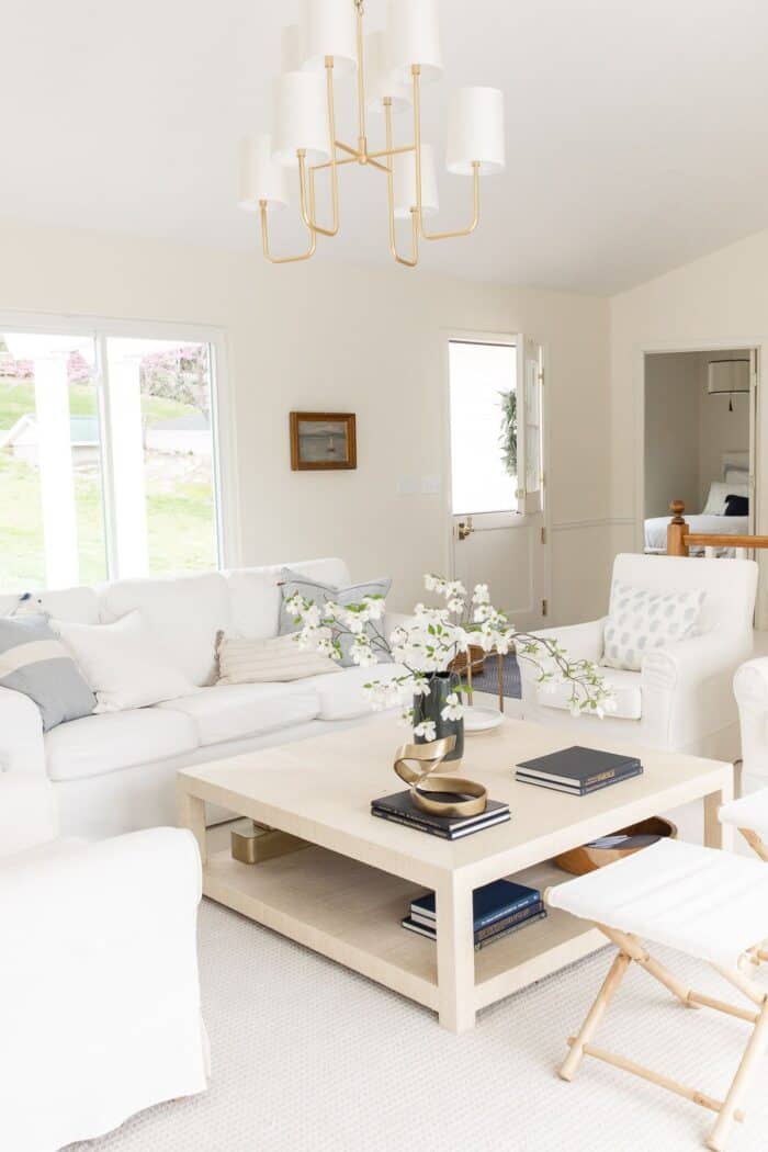 A coastal modern living room featuring white furniture and a brass chandelier.