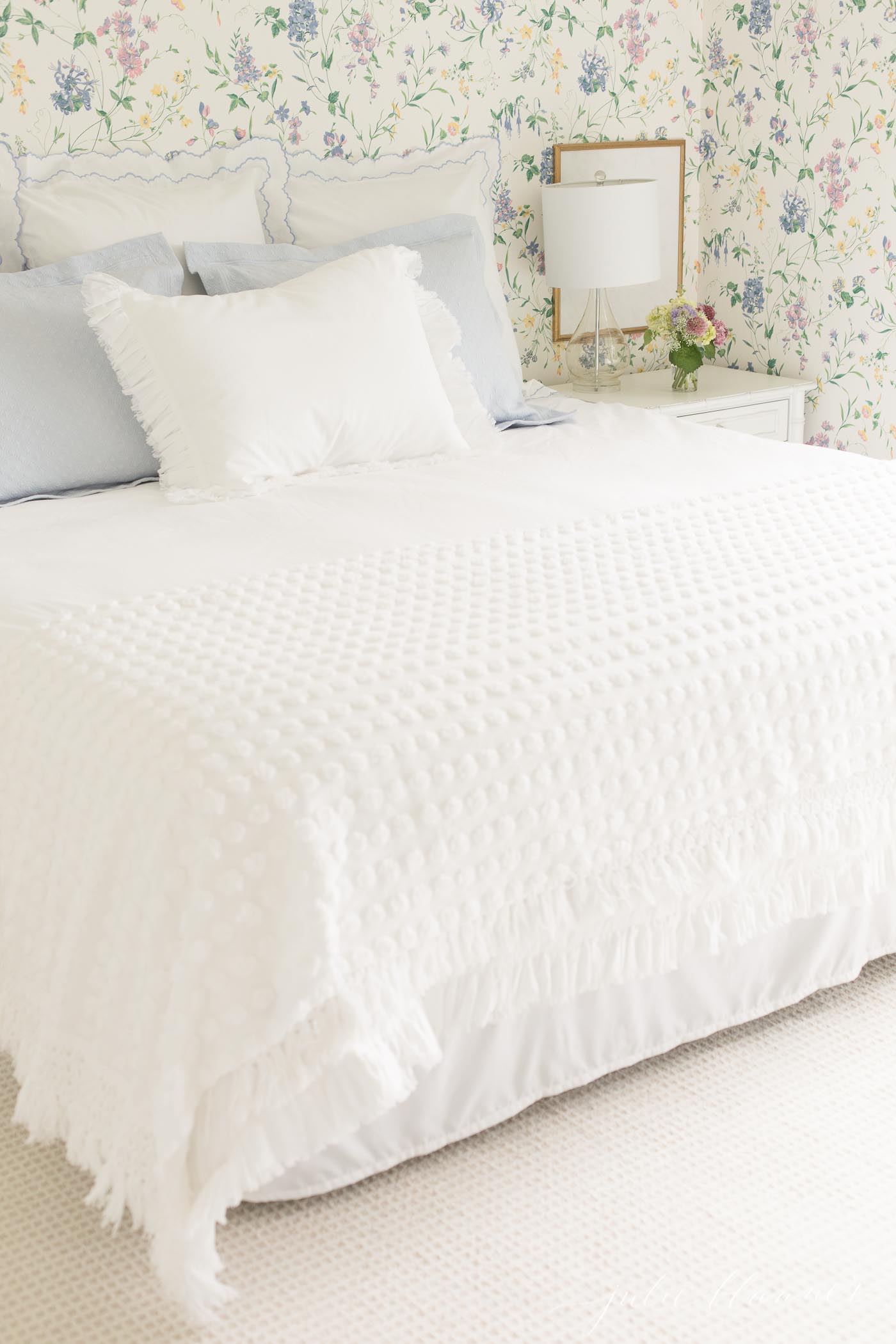 A floral wallpapered guest bedroom with king size bed