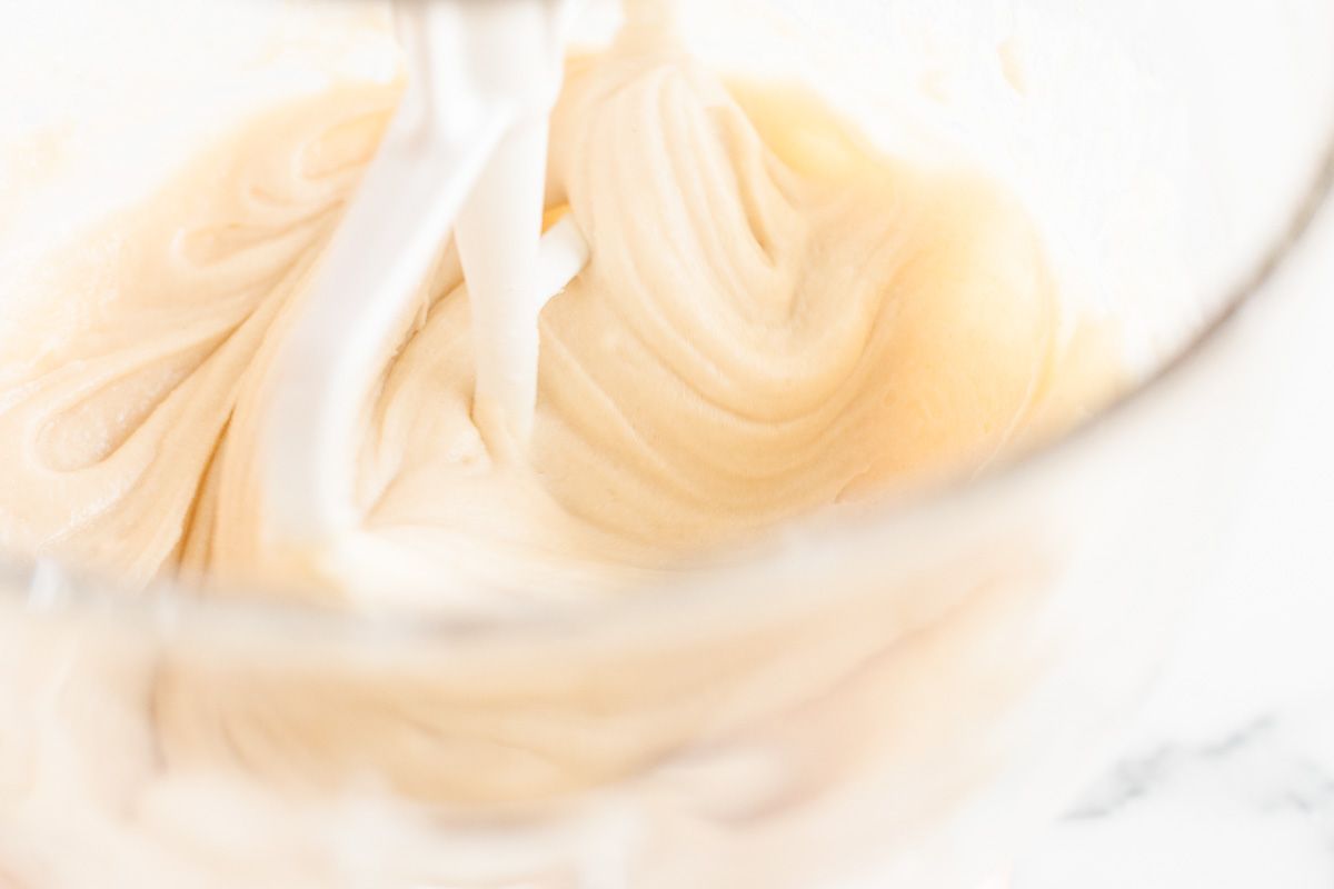 A batter coming together in a clear glass bowl of a stand mixer