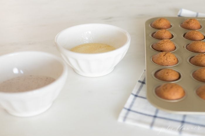 Baked pumpkin muffins next to bowls with the toppings