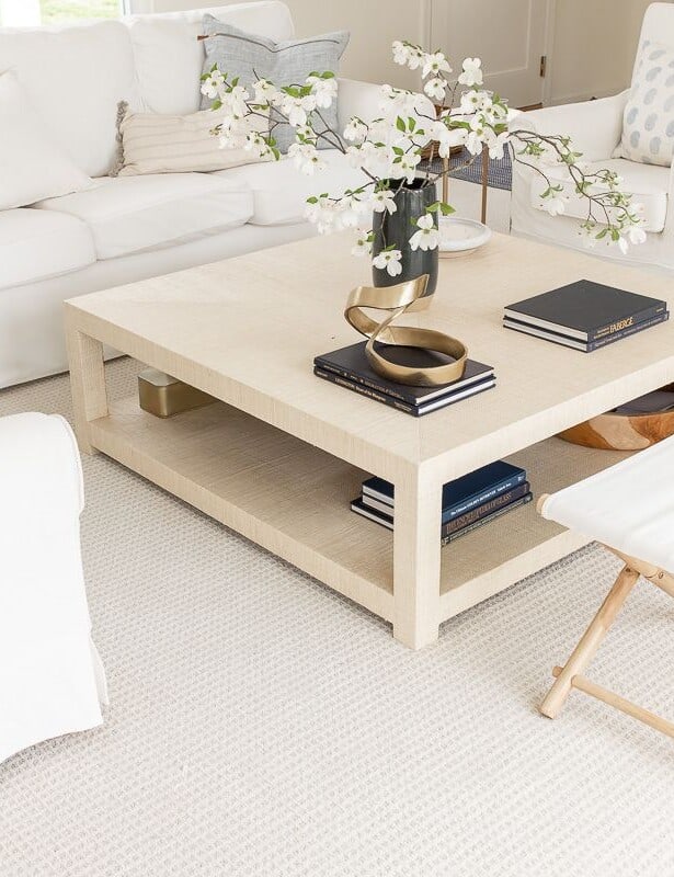 A white living room with white furniture and a raffia coffee table.