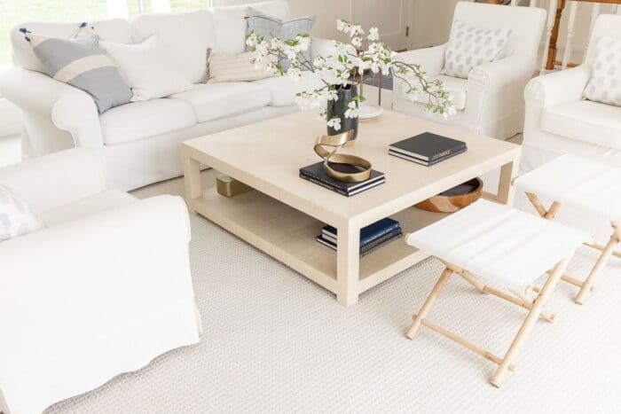 A white living room with white furniture and a raffia coffee table.