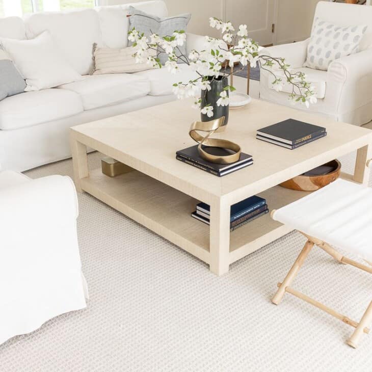 A white living room with white furniture and a raffia coffee table.