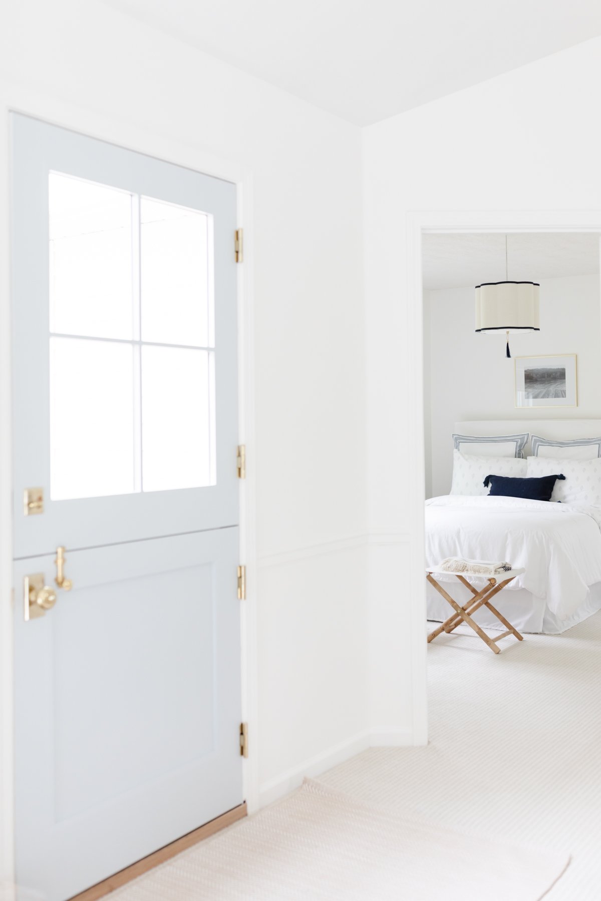 A white room with a light blue Dutch door and wall to wall carpet.