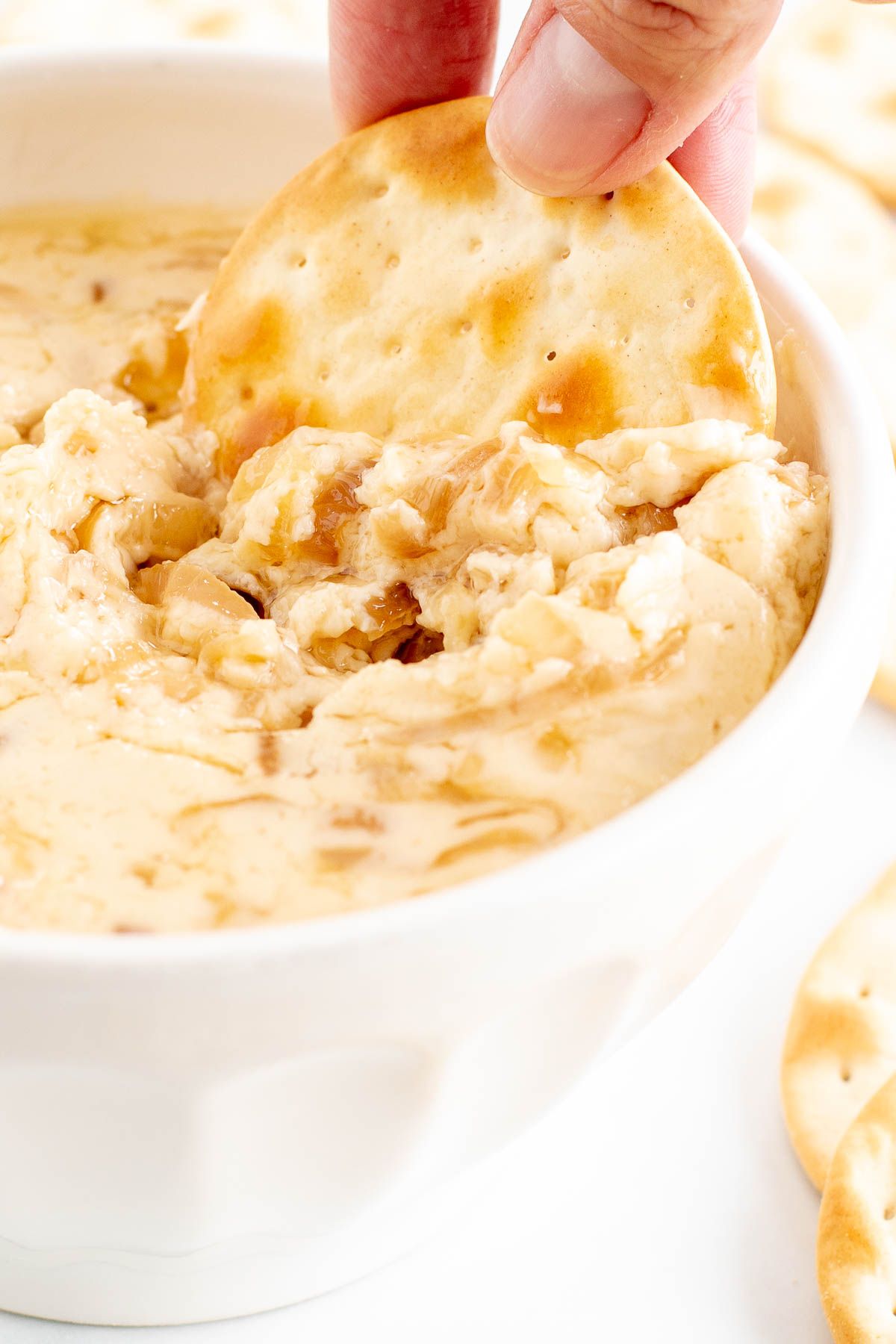 A white bowl of caramelized shallot dip surrounded by crackers