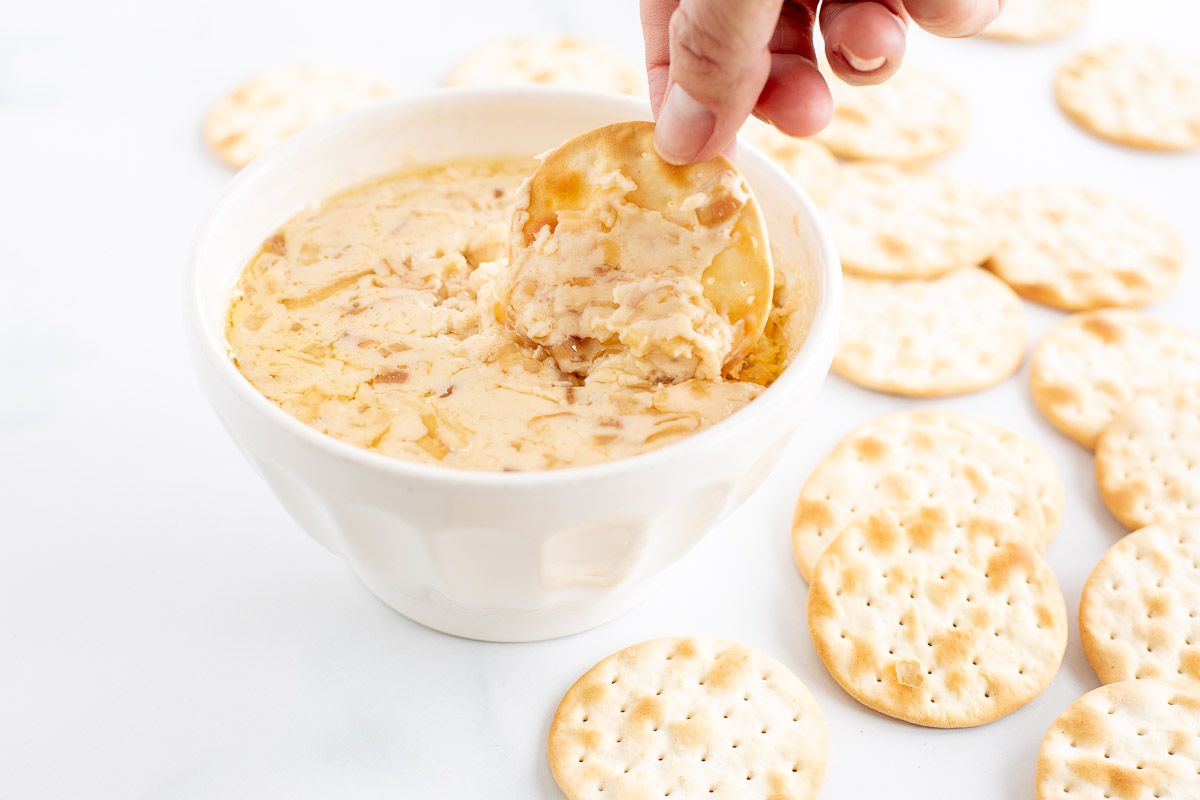 A white bowl of caramelized shallot dip surrounded by crackers