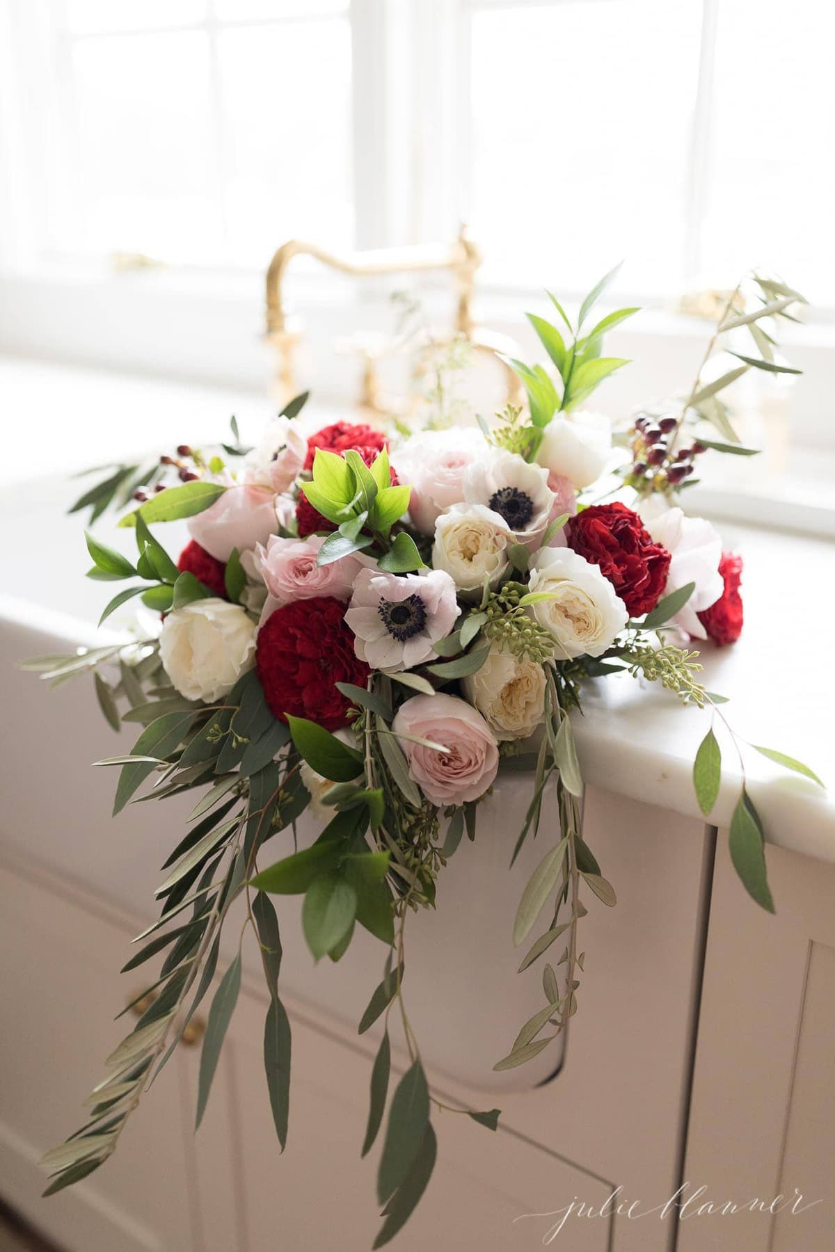A red and pink christmas flower arrangement in a farm sink