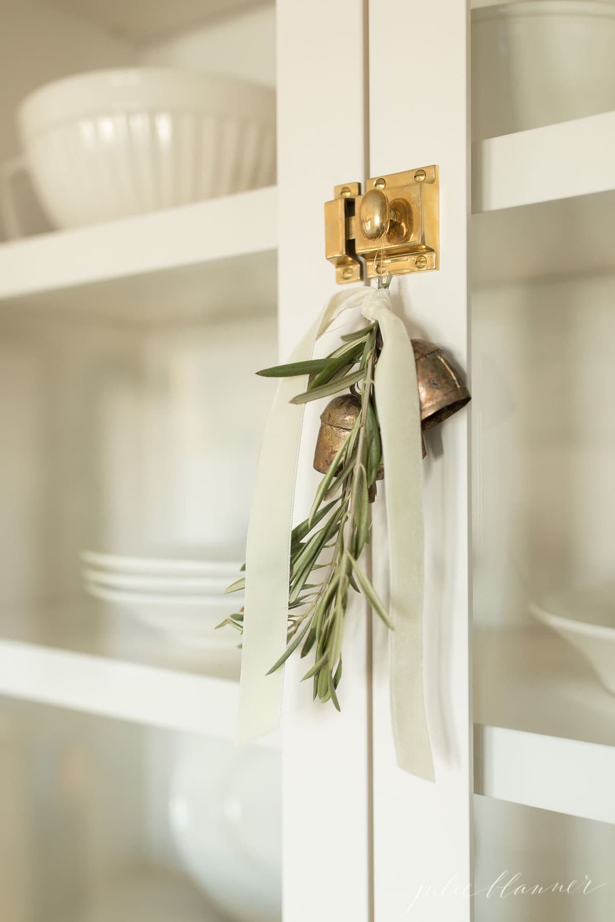 greenery with bells and velvet ribbon hanging from kitchen cupboard