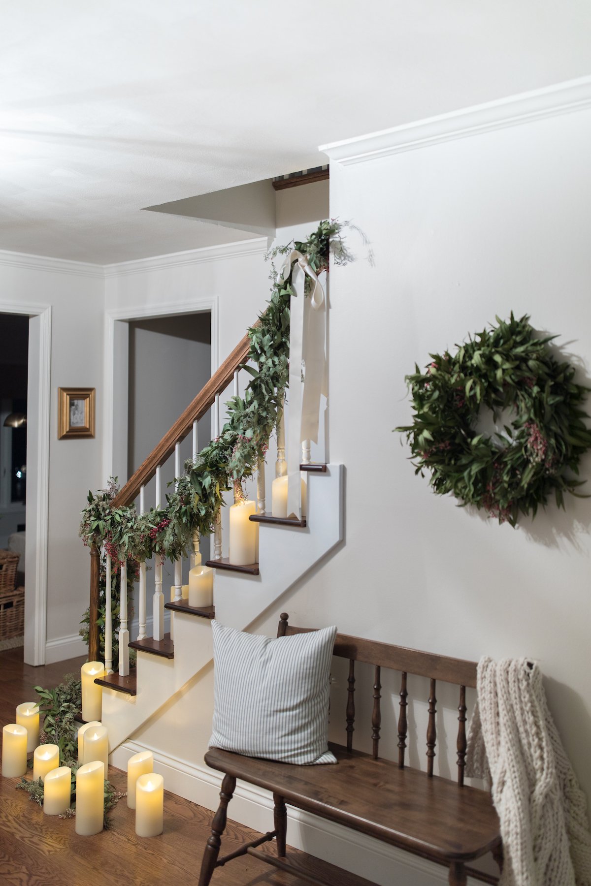 A Christmas hallway adorned with candles and featuring a cozy bench.