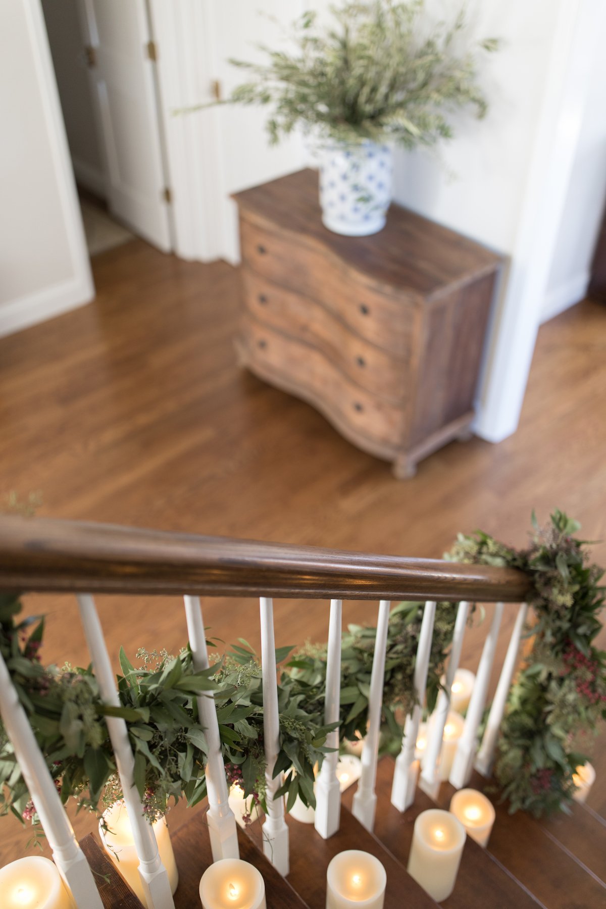 A Christmas house staircase adorned with candles and greenery.