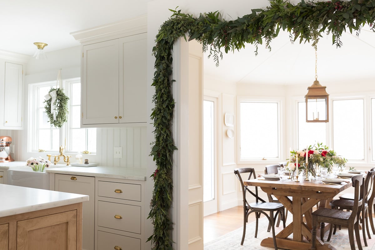 A Christmas house with a kitchen adorned with a festive garland in the dining room.