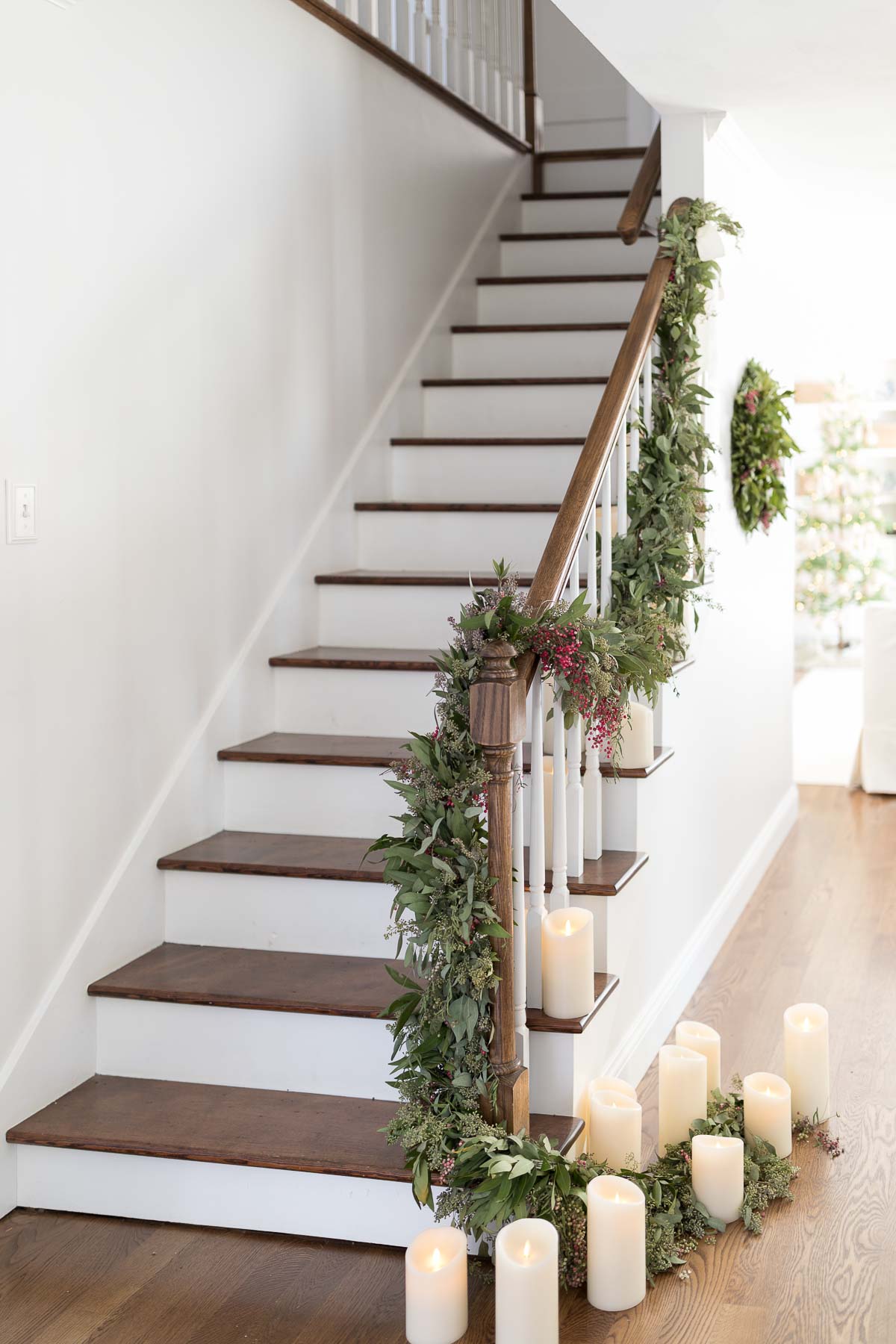 A Christmas house staircase adorned with greenery and candles.