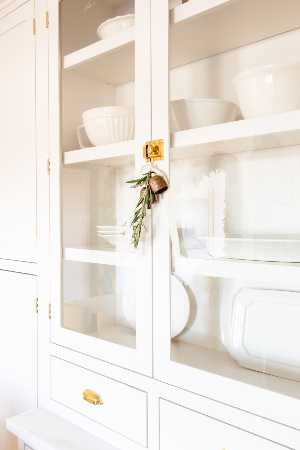 A white china cabinet with gold handles and plates, perfect for adding festive charm to your Christmas house.