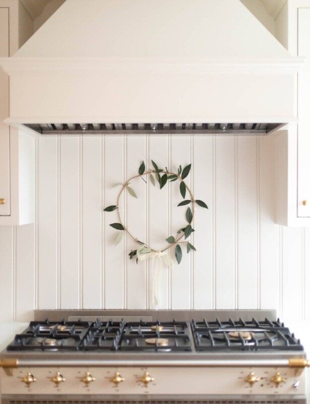 A cream kitchen with a simple greenery wreath hanging behind the range.