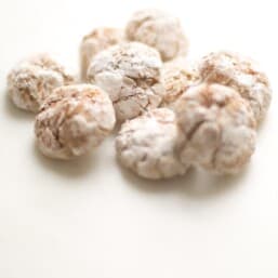 pile of eggnog cookies dusted in powdered sugar and spices on white surface