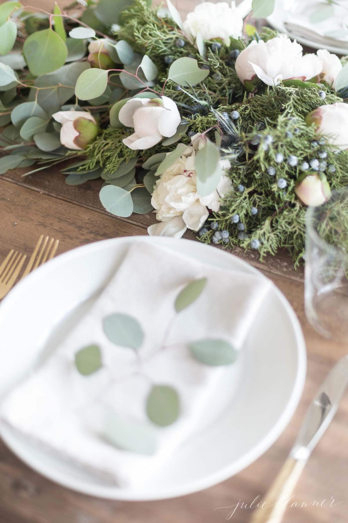 Christmas greens and fresh blooms on a dining room table.